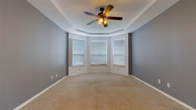 carpeted empty room with ceiling fan and a tray ceiling