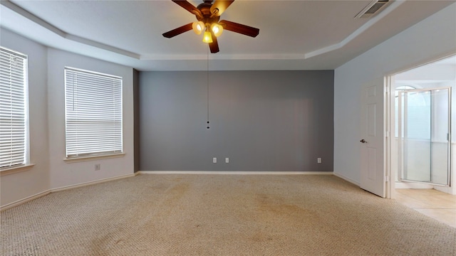 carpeted spare room with a tray ceiling and ceiling fan