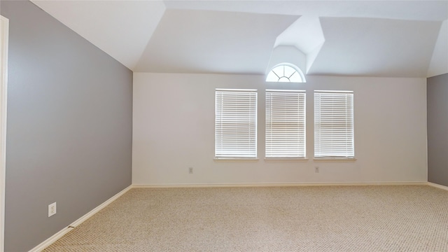 carpeted empty room featuring lofted ceiling