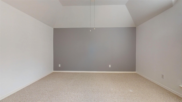 carpeted spare room with vaulted ceiling