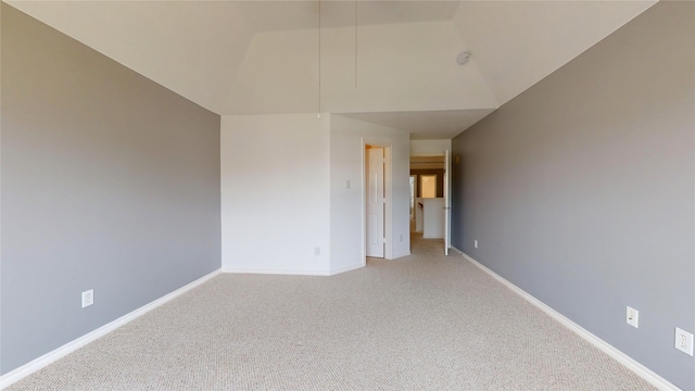 carpeted spare room with vaulted ceiling