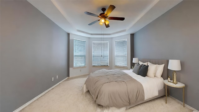 bedroom featuring ceiling fan, light carpet, and a raised ceiling