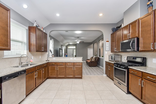 kitchen with sink, kitchen peninsula, appliances with stainless steel finishes, tasteful backsplash, and lofted ceiling