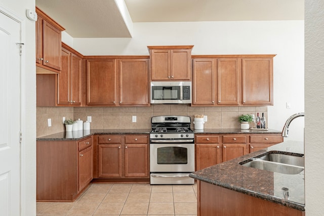 kitchen with appliances with stainless steel finishes, sink, backsplash, and light tile patterned flooring