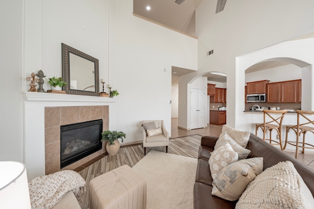 living room with high vaulted ceiling, a fireplace, and hardwood / wood-style floors