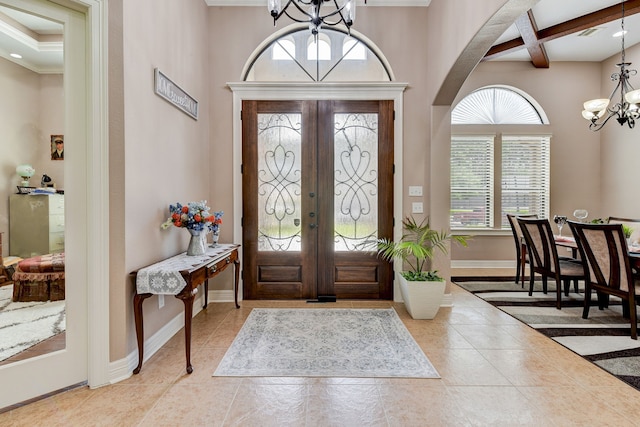 entryway with beamed ceiling, a notable chandelier, light tile patterned floors, coffered ceiling, and french doors