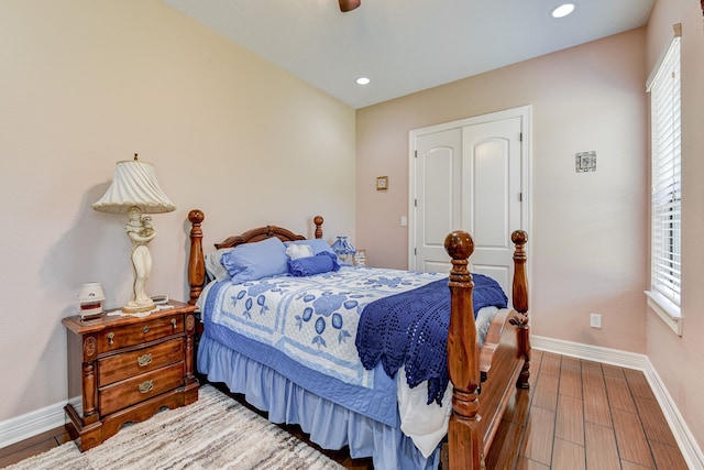 bedroom featuring a closet, multiple windows, hardwood / wood-style floors, and ceiling fan