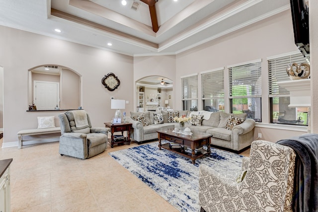 living room with a high ceiling, ceiling fan, a raised ceiling, and ornamental molding