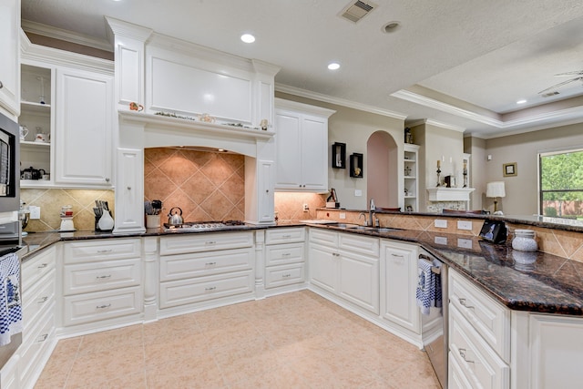 kitchen with dark stone counters, white cabinetry, sink, and crown molding