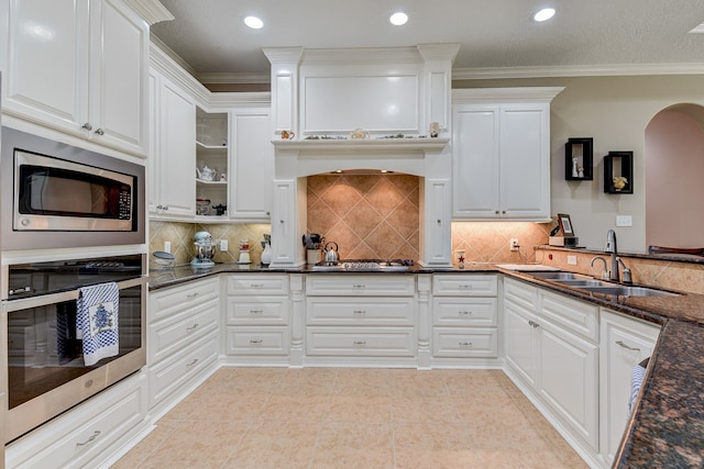 kitchen with dark stone counters, white cabinets, sink, crown molding, and appliances with stainless steel finishes