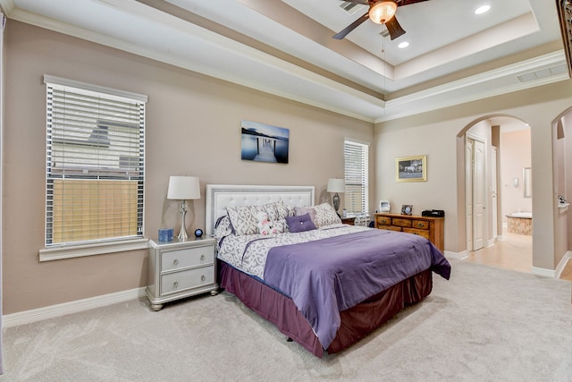 carpeted bedroom with ensuite bathroom, a raised ceiling, ceiling fan, and crown molding