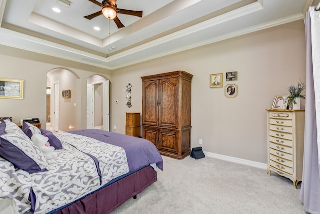 carpeted bedroom with ornamental molding, ceiling fan, and a raised ceiling