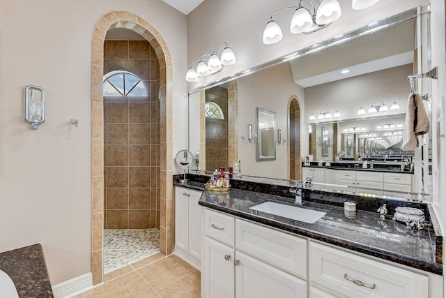 bathroom with tile patterned flooring, vanity, and a tile shower