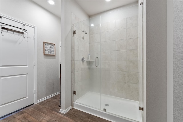 bathroom featuring wood-type flooring and a shower with shower door