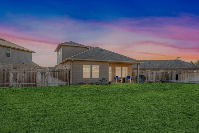 back house at dusk featuring a yard