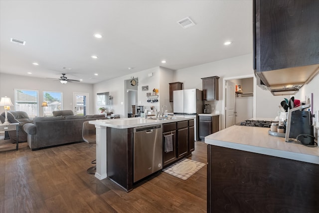 kitchen with dark hardwood / wood-style flooring, a center island with sink, exhaust hood, stainless steel dishwasher, and dark brown cabinets