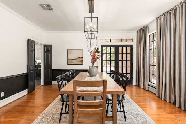 dining area featuring hardwood / wood-style flooring, plenty of natural light, crown molding, and french doors