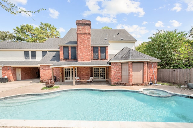 rear view of house with french doors, a patio area, and a pool with hot tub