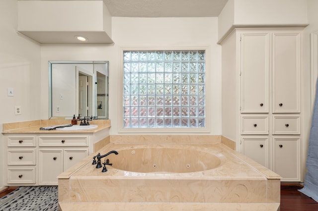 bathroom with a tub to relax in, vanity, and a textured ceiling