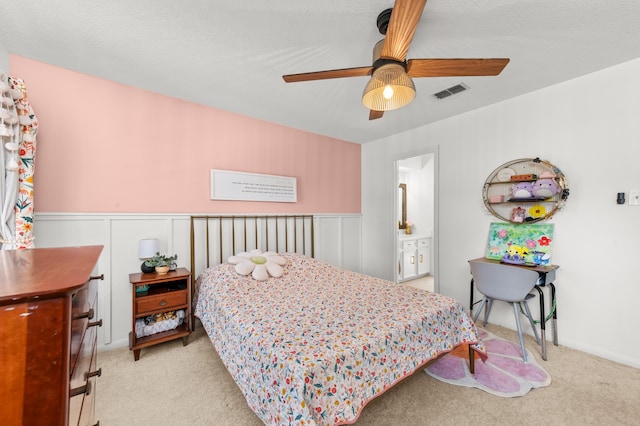 bedroom with a textured ceiling, light colored carpet, ceiling fan, and ensuite bathroom