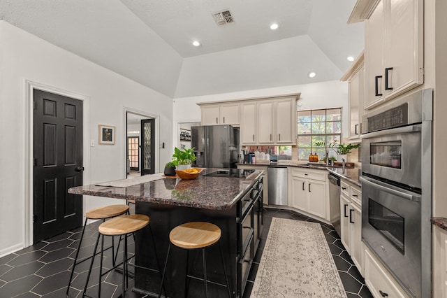 15007 Terrace Oaks Dr, Houston, TX 77068 - kitchen with black appliances, a kitchen island, a kitchen bar, dark stone counters, and recessed lighting