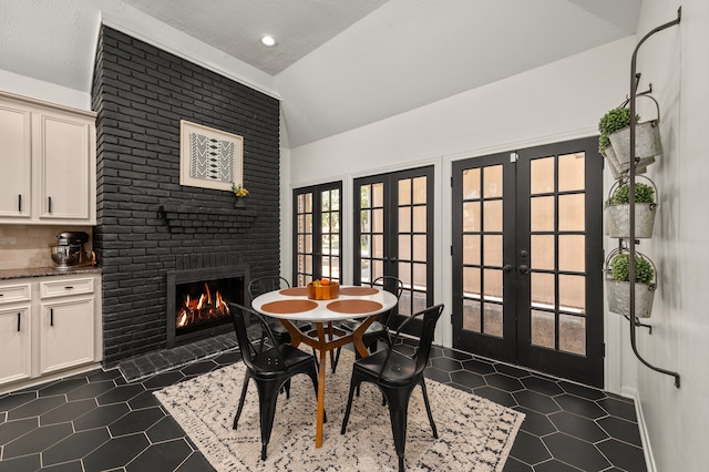 dining area featuring french doors, a textured ceiling, vaulted ceiling, and a brick fireplace