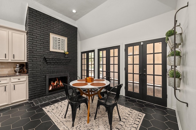 15007 Terrace Oaks Dr, Houston, TX 77068 - dining area featuring french doors, lofted ceiling, dark tile patterned flooring, and a brick fireplace