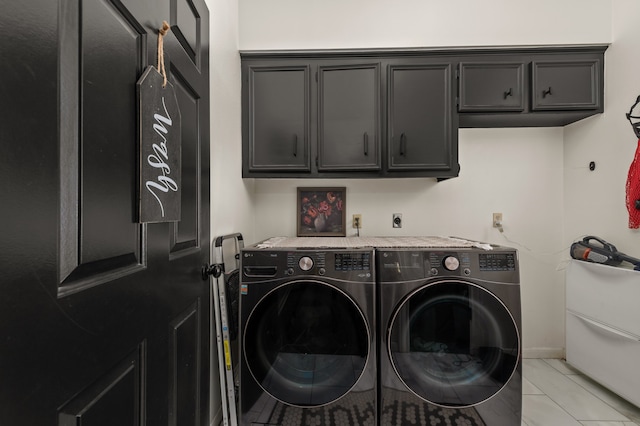 clothes washing area with washing machine and clothes dryer, light tile patterned floors, and cabinets