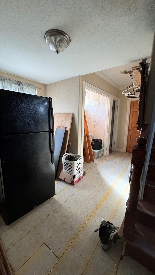 interior space featuring black refrigerator, a textured ceiling, and ornamental molding