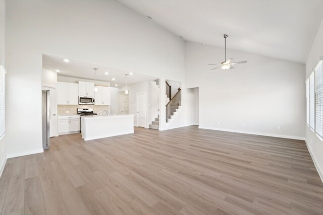 unfurnished living room featuring ceiling fan, light hardwood / wood-style flooring, and high vaulted ceiling