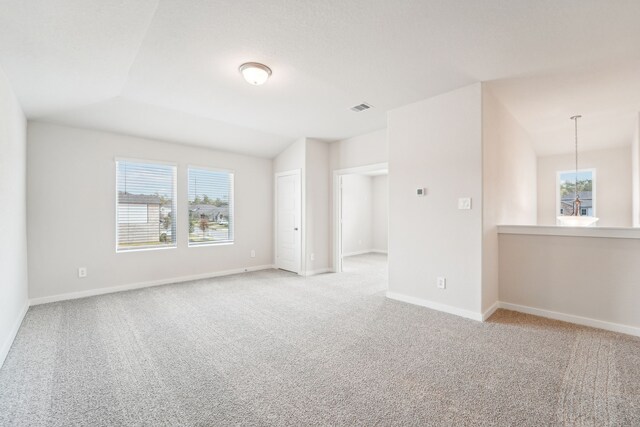 carpeted spare room featuring vaulted ceiling