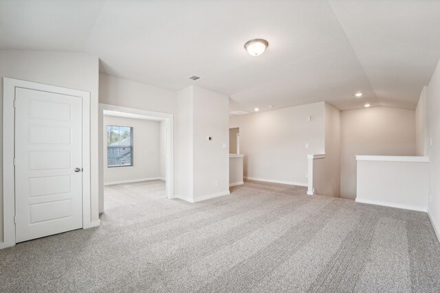 carpeted empty room with vaulted ceiling