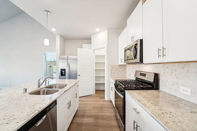 kitchen with white cabinets, sink, stainless steel appliances, and hanging light fixtures