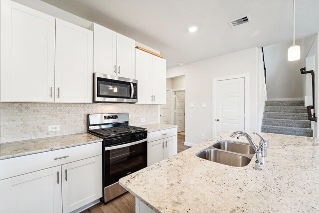 kitchen with white cabinets, sink, light stone countertops, dark hardwood / wood-style flooring, and stainless steel appliances