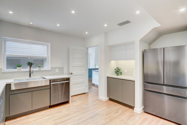 kitchen with gray cabinets, appliances with stainless steel finishes, sink, white cabinets, and light hardwood / wood-style flooring