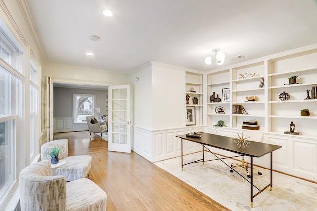 home office with french doors, crown molding, built in shelves, and light hardwood / wood-style floors