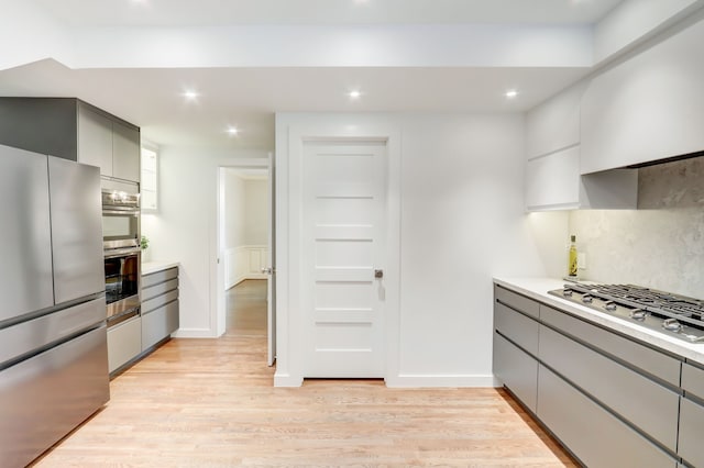 kitchen featuring stainless steel appliances, gray cabinetry, backsplash, and light hardwood / wood-style floors