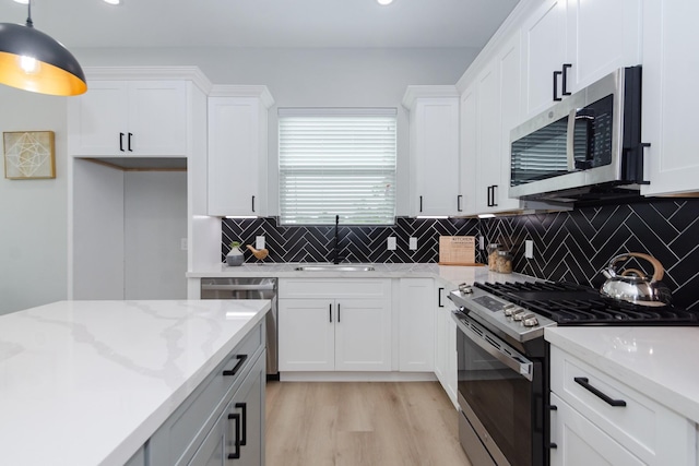 kitchen with white cabinets, decorative light fixtures, and stainless steel appliances