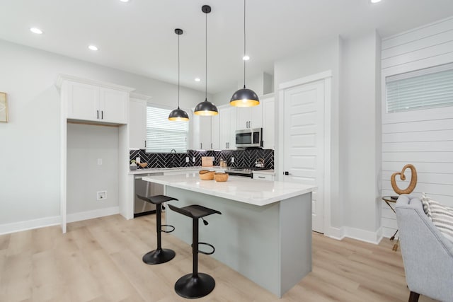 kitchen with pendant lighting, a center island, stainless steel appliances, and white cabinetry