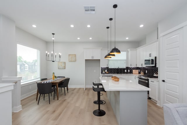 kitchen with white cabinetry, hanging light fixtures, a kitchen island, and stainless steel appliances