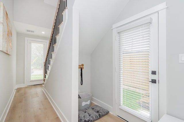 foyer with plenty of natural light, vaulted ceiling, and light hardwood / wood-style flooring