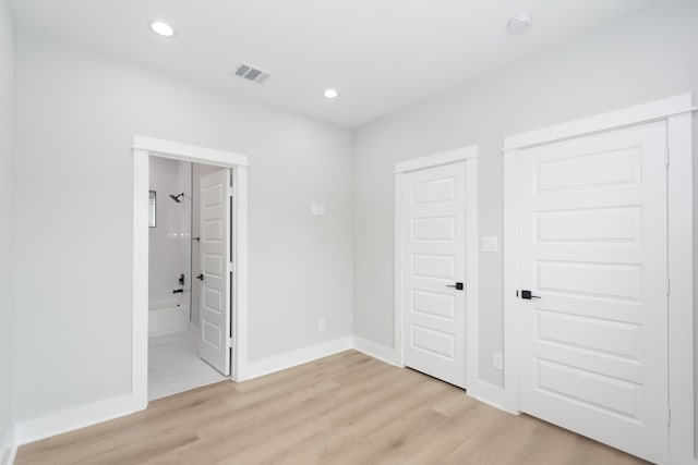 unfurnished bedroom featuring light wood-type flooring and connected bathroom