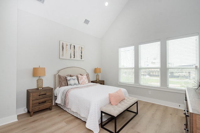 bedroom with high vaulted ceiling, light hardwood / wood-style flooring, and multiple windows