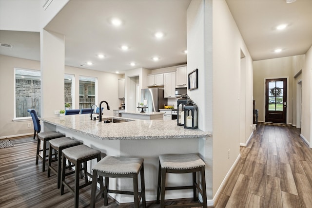 kitchen featuring a kitchen bar, white cabinets, kitchen peninsula, sink, and dark hardwood / wood-style floors