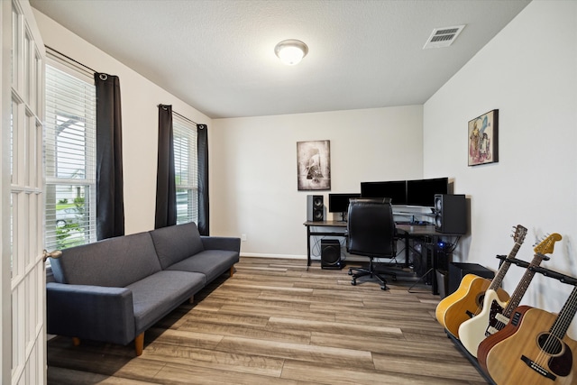 office space with wood-type flooring, a healthy amount of sunlight, and a textured ceiling