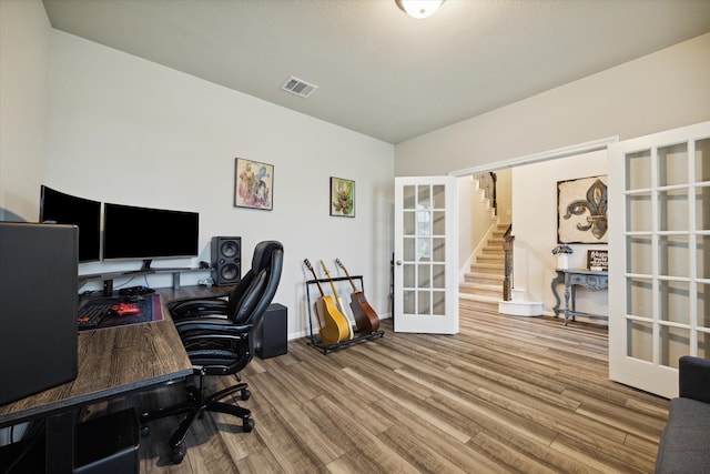 home office with a textured ceiling, hardwood / wood-style floors, and french doors