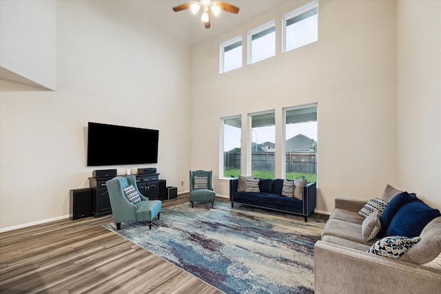 living room featuring hardwood / wood-style floors, a towering ceiling, and ceiling fan