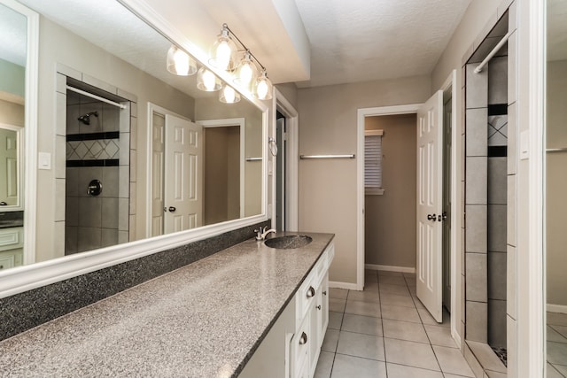 bathroom with tile patterned flooring, tiled shower, a textured ceiling, and vanity