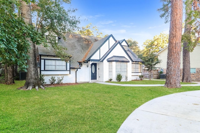 488 Stephen F Austin Dr, Conroe, TX 77302 - tudor home with a front yard, central AC unit, roof with shingles, and brick siding