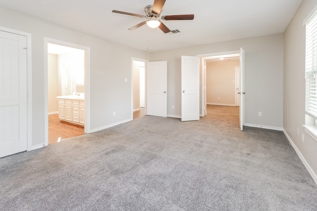 unfurnished bedroom featuring ensuite bath, ceiling fan, and light colored carpet